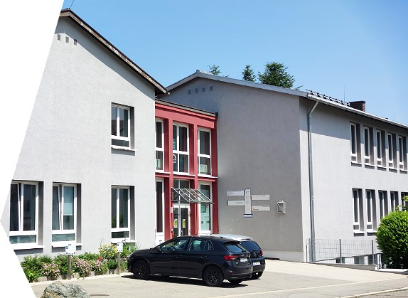 Das Schulungsgebäude der bfz Pflegeschule, bfz gGmbH und der gfi gGmbH in Immenstadt Gebäude grau, Eingang rot